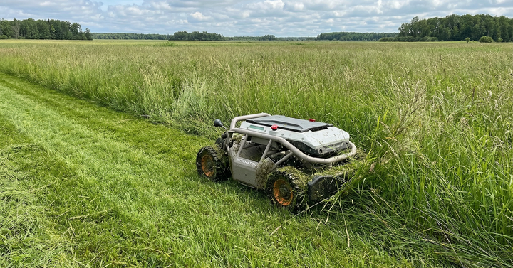 Ein fortschrittlicher Mähroboter bahnt sich effizient einen Weg durch eine riesige, wilde Wiese mit extrem hohem Gras unter bewölktem Himmel und zeigt professionelles Vegetationsmanagement im Außenbereich.